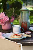Bread and jam and small posy on rustic table in garden