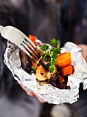 A woman holding vegetables in tin foil