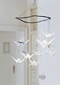 Wire mobile hung with origami cranes made from newspaper and writing paper