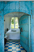 Bedroom with blue and white patterned floor and turquoise oriental-style wooden door
