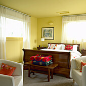Schlafzimmer mit Holzbett und farbenfrohen Kissen
