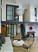 Bauhaus armchair in front of upholstered sofa and view of gallery in loft-apartment