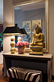 Konsole mit goldener Buddha-Statue und Tischlampe vor Wandspiegel