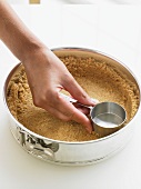 Pressing Crumb Crust into a Plan with Measuring Cup