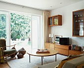 50s-style living room with floor to ceiling terrace windows and view of garden