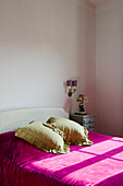 Bedroom with white bed, pink bedspread and light green cushions