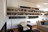 Modern living room with narrow, horizontal window between long bookshelves and sideboard