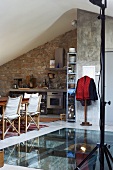 Dining area next to cut-away in floor with glass panel in rustic, modern kitchen