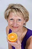 A woman holding half an orange