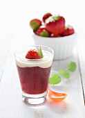 Strawberry compote with vanilla sauce in dessert glass on wooden table