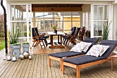 Wooden loungers with cushions on terrace adjoining conservatory