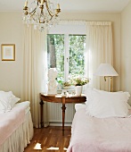 Romantic, vintage-style guest room with classical console table below window and twin beds with valances