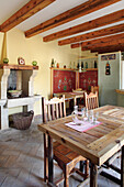 Rustic room with wooden dining table, ceiling beams and tiled floor