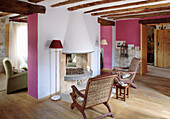 Country-style living room with fireplace, wooden beams and pink accent walls