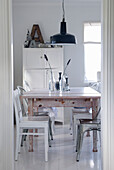 Small vintage-style dining area with white furniture, dining table and black pendant light