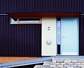 Front door in dark corrugated metal facade with metal ramp