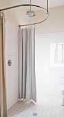 Simple, modern shower with curtain hung on suspended, curved steel tube