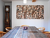 Rustikaler Esstisch und Stühle vor abstraktem Bild an Wand
