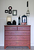 Antique wooden chest of drawers with decorative items and wall lamp