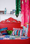 Rotes Daybed mit bunten Kissen und verziertem Kopfteil