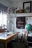 Arbeitsplatz mit Vintage-Schreibtisch, Globus und ethnischen Dekorationen
