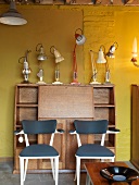 Bureau with desk lamps in front of yellow wall