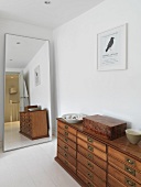 A chest of drawers next to a full-length mirror