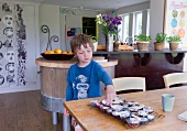 Boy in kitchen takes muffin from cooling rack
