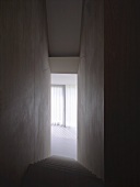 Narrow, high stairwell without handrail and view of sunny room with vertical blinds