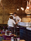English restaurant in hall with exposed brick wall and hams hanging over historic counter