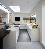 Sunny, designer kitchen with sophisticated two-tone colour scheme featuring modern mineral materials and dark wood counter