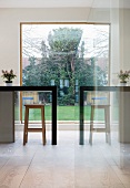 Reflection of counter with bar stool in front of panoramic window with view of garden