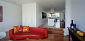 Langgestreckter, offener Wohnraum mit Sofa & Treppe zur Küche