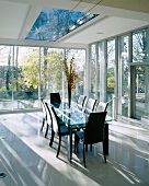 Black leather chairs at glass-topped dining table in front of glass facade