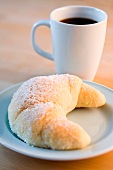 A quark croissant with sugar and a cup of coffee