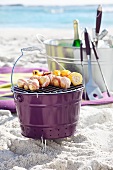 Bucket barbecue with skewers on sandy beach