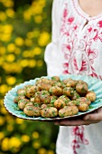 Woman holding plate with roasted herb potatoes