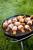 Bacon-wrapped chicken legs on barbecue