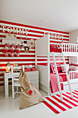 White bunk beds against red and white striped wall with matching rug in children's bedroom