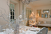 Festively set table in front of illuminated Christmas tree in white living-dining room