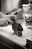 Cutting a fried T-bone steak into pieces along the bone
