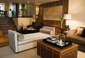 Tray on antique trunk in front of light upholstered couch in modern, split-level living space