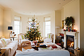 Light sofa set in traditional interior with Christmas tree in window bay