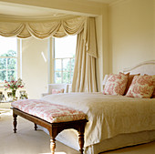 Elegant bedroom with draped pelmet in front of bay window