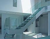 Glass staircase leading from dining room to upper storey