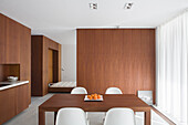 Dining table with white chairs in modern room with wooden furniture and wooden partition wall