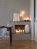 Fireplace with candles, white decor and wooden table in the living room