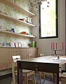 Dining table with chairs in front of open shelving and a sideboard in a wall niche