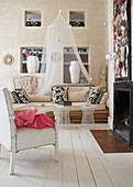 Sessel mit weißem Lederbezug und Sofa aus Bambusstangen vor Kamin in modernem Landhaus