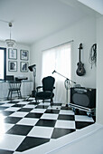Music corner with black baroque armchair, electric guitar and amplifier on checkered pattern floor